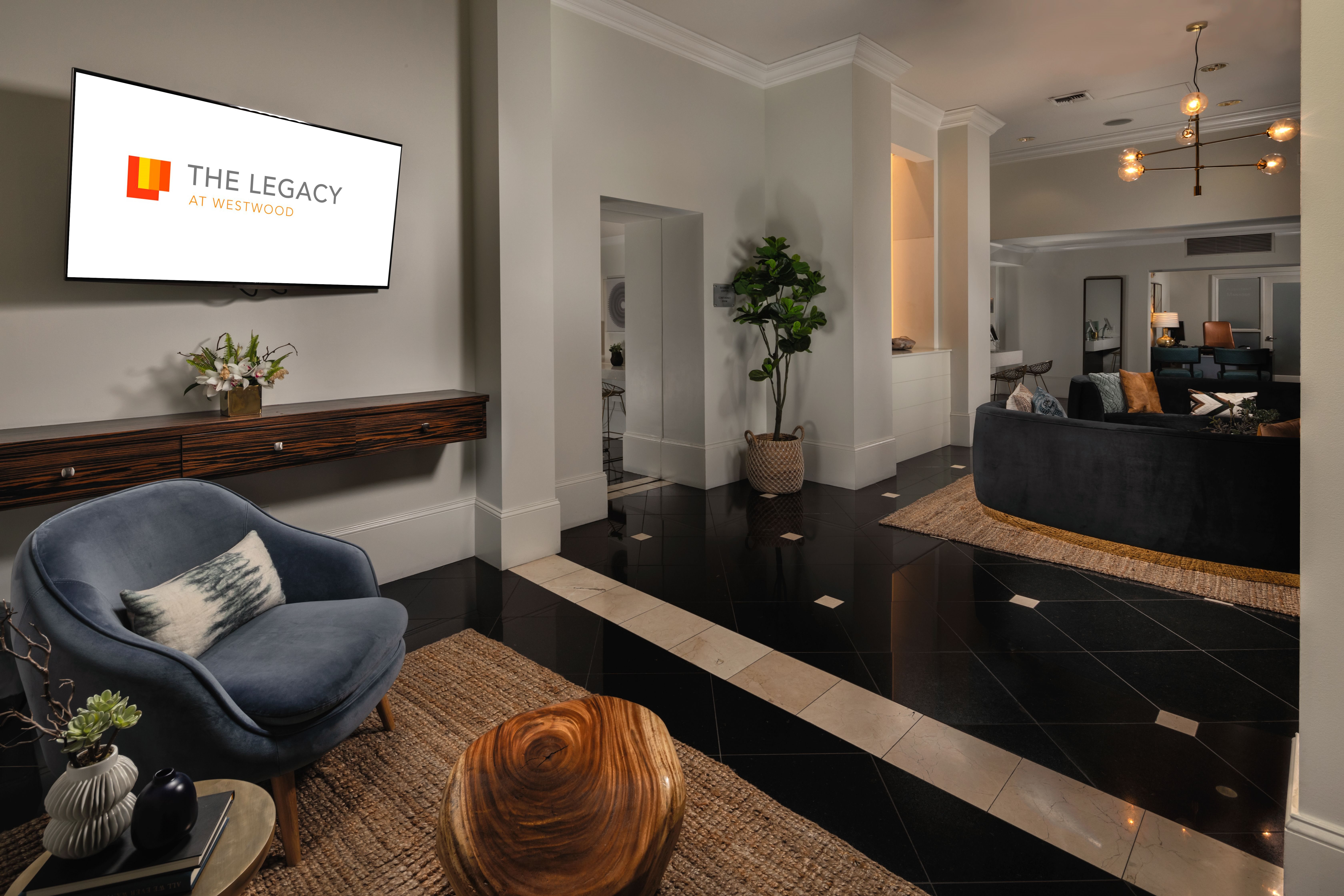 A living room with a blue chair and a sign that says "The Legacy at Westwood".