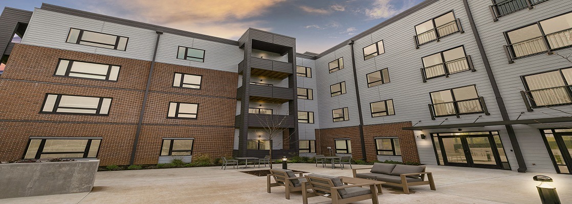a courtyard with a fire pit and patio furniture in front of an apartment building