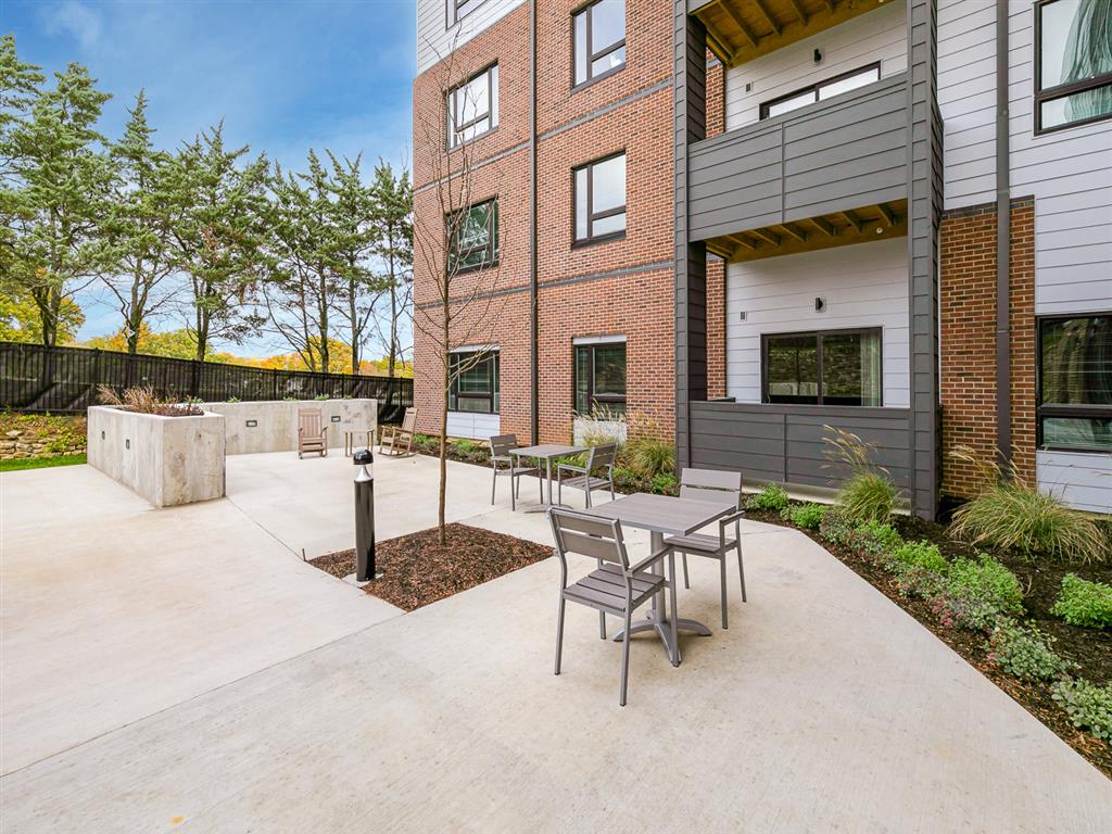 a patio with a table and chairs and a fire pit in front of a brick building