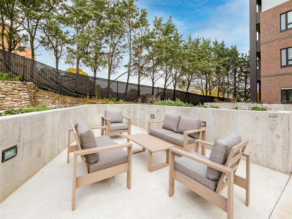 a patio with wooden furniture and a stone wall