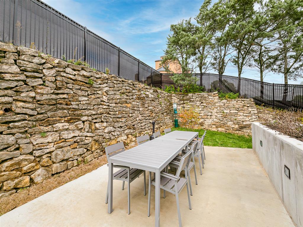 a patio with a wooden table and chairs and a stone wall