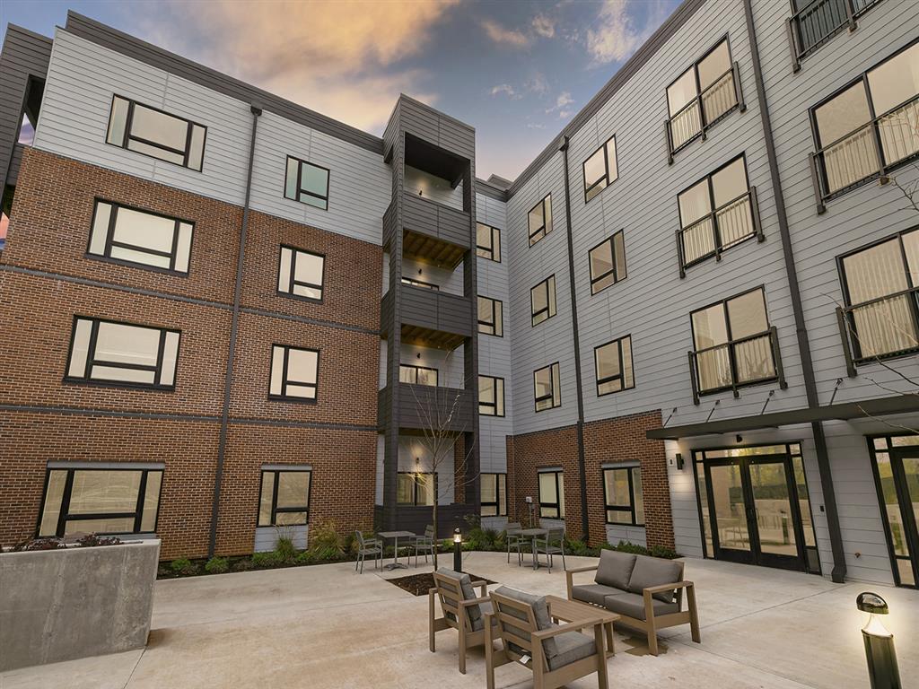 a courtyard with a fire pit and patio furniture in front of a brick building