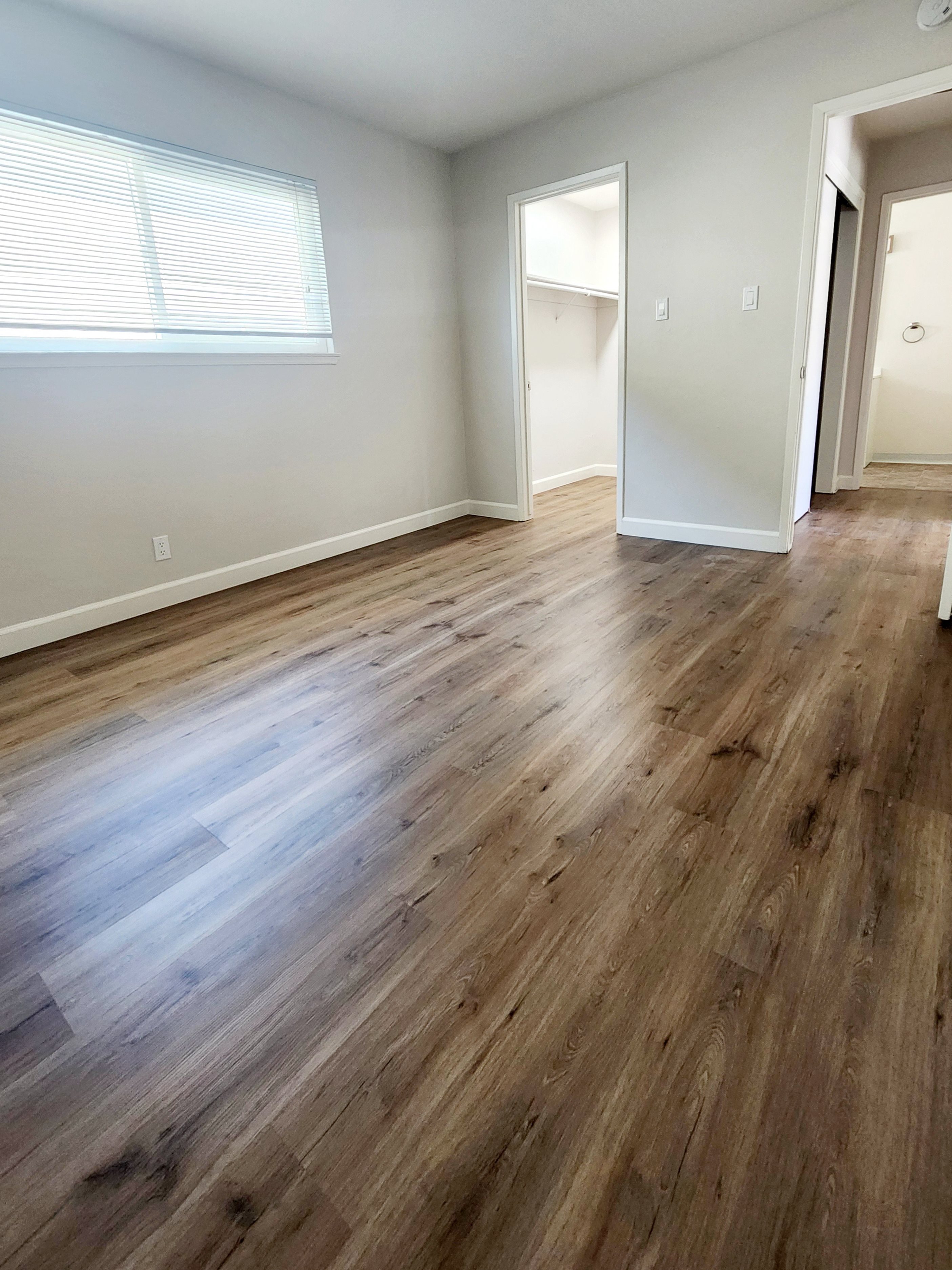 an empty living room with hardwood flooring and a window