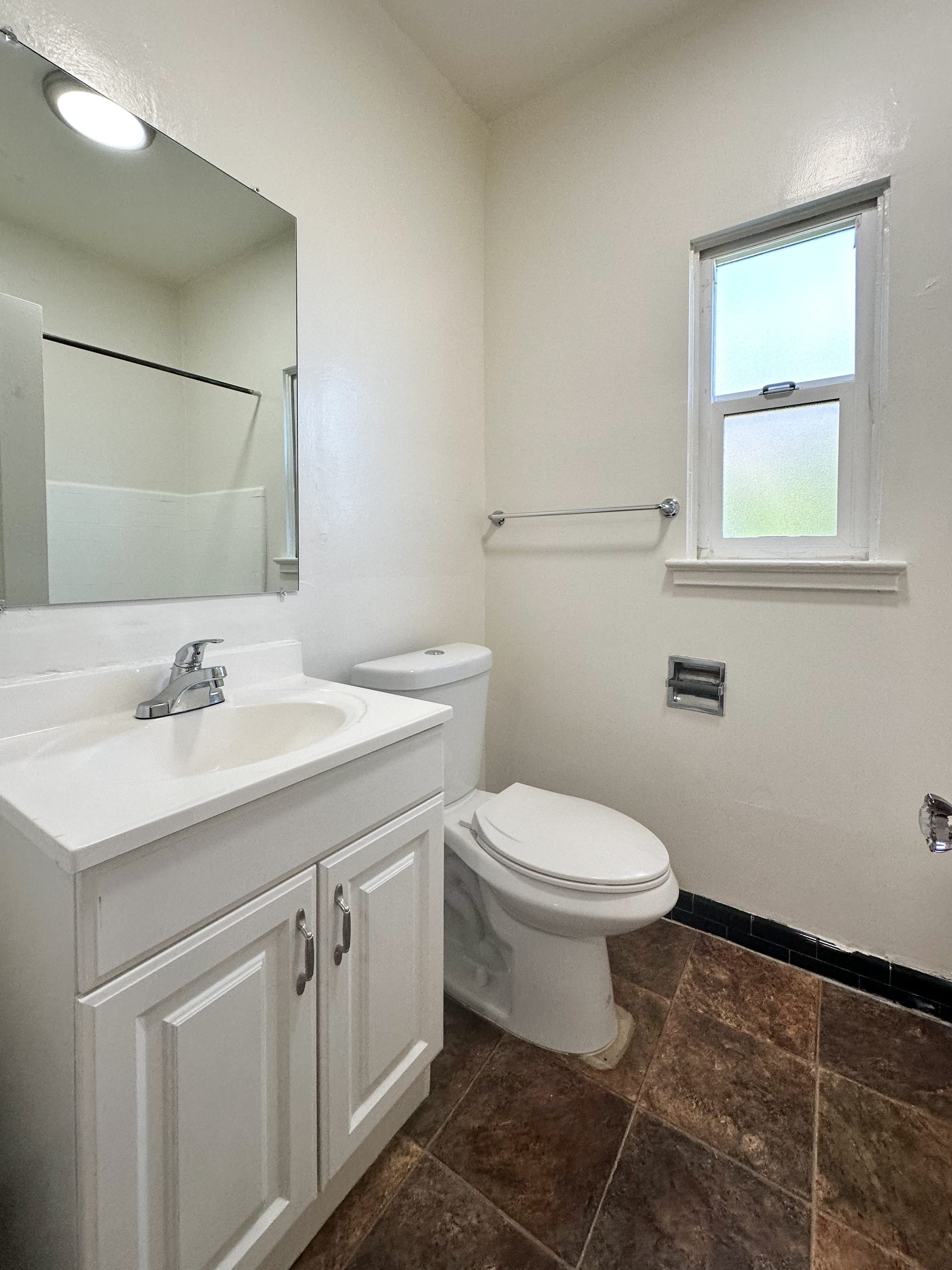 A white toilet sits in a bathroom next to a sink and a mirror.