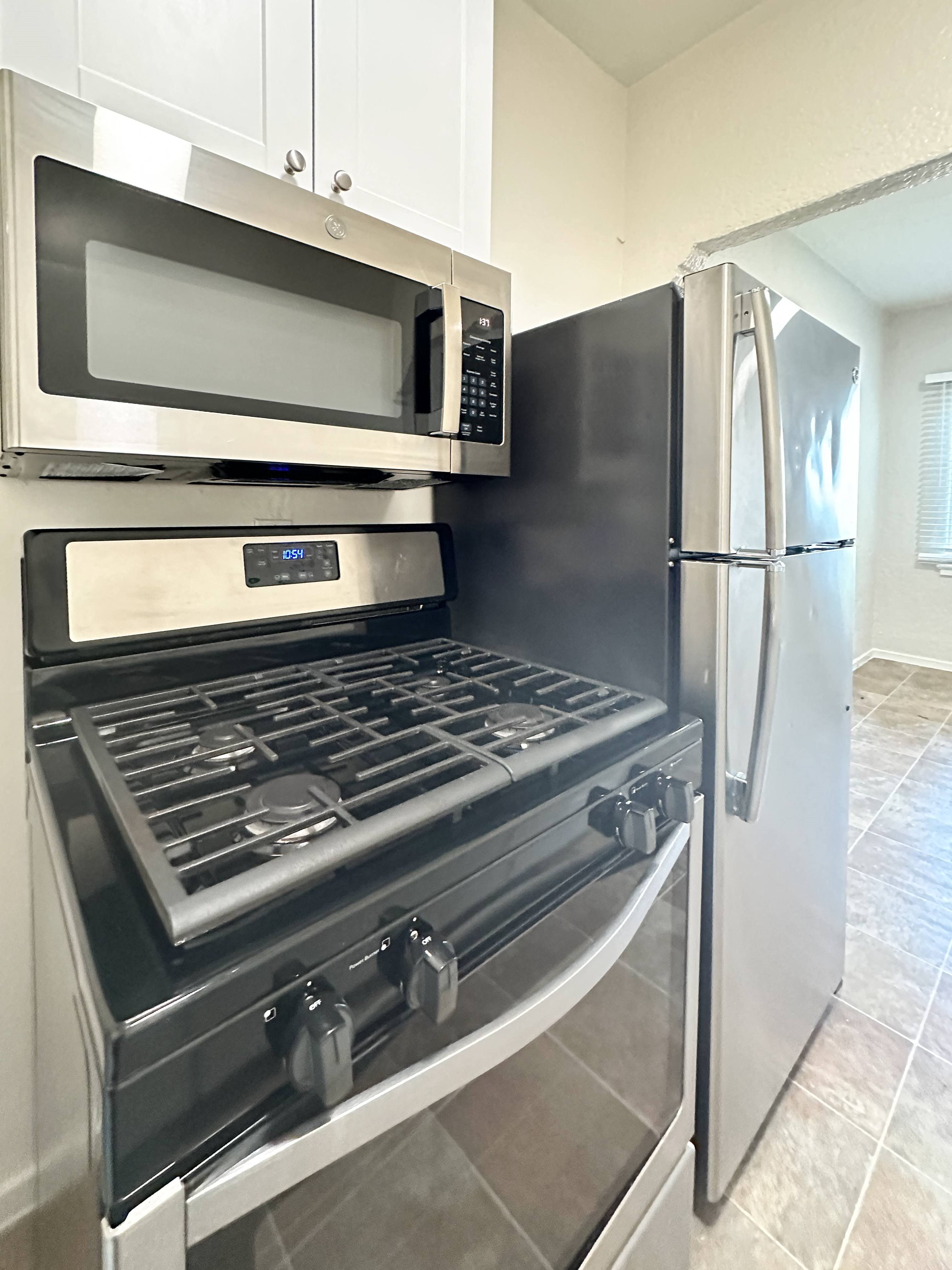 A black stove top oven with a silver microwave above it.