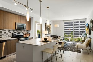 A modern kitchen with a large island and a dining area with chairs.