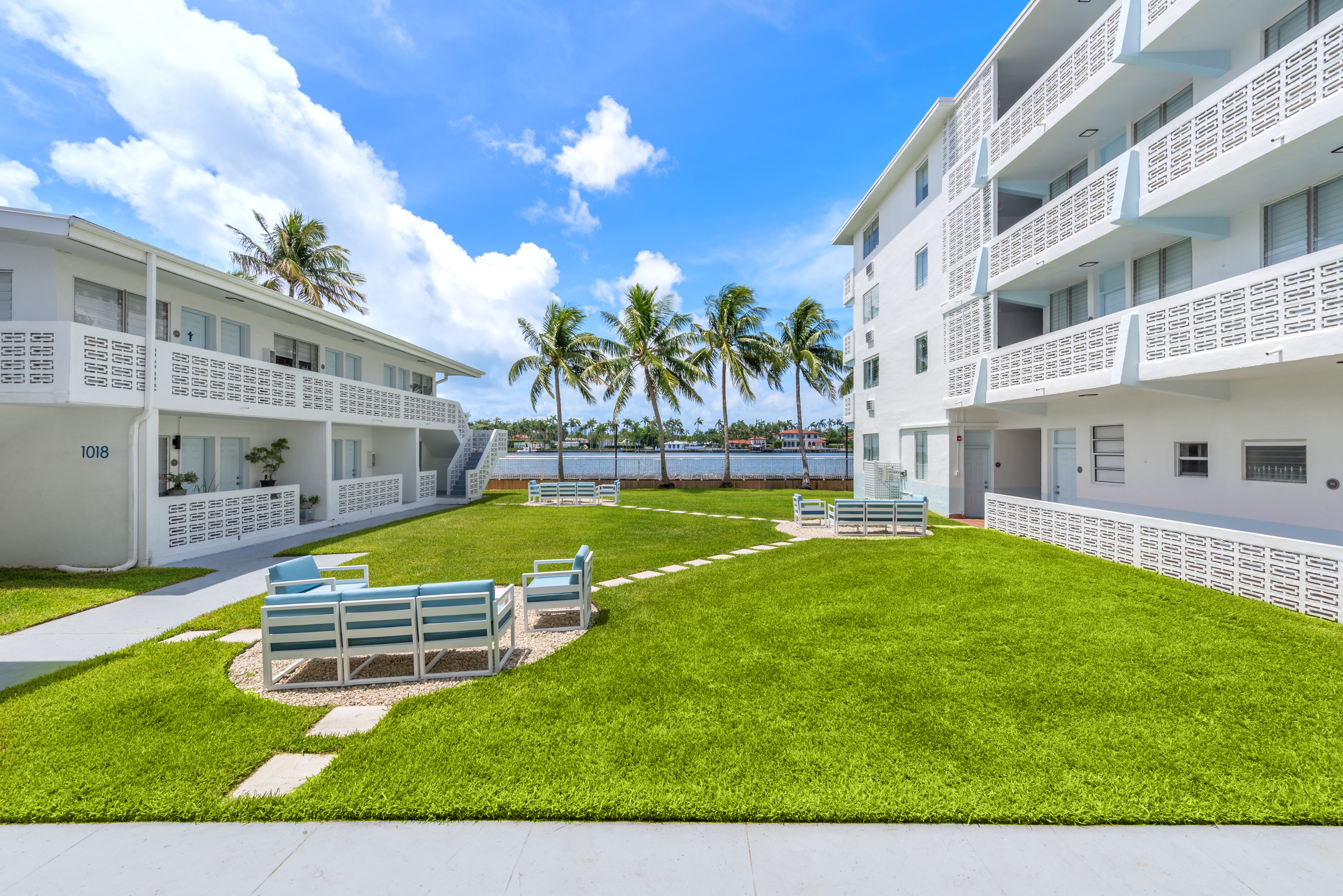 A white building with balconies and a green lawn in front.