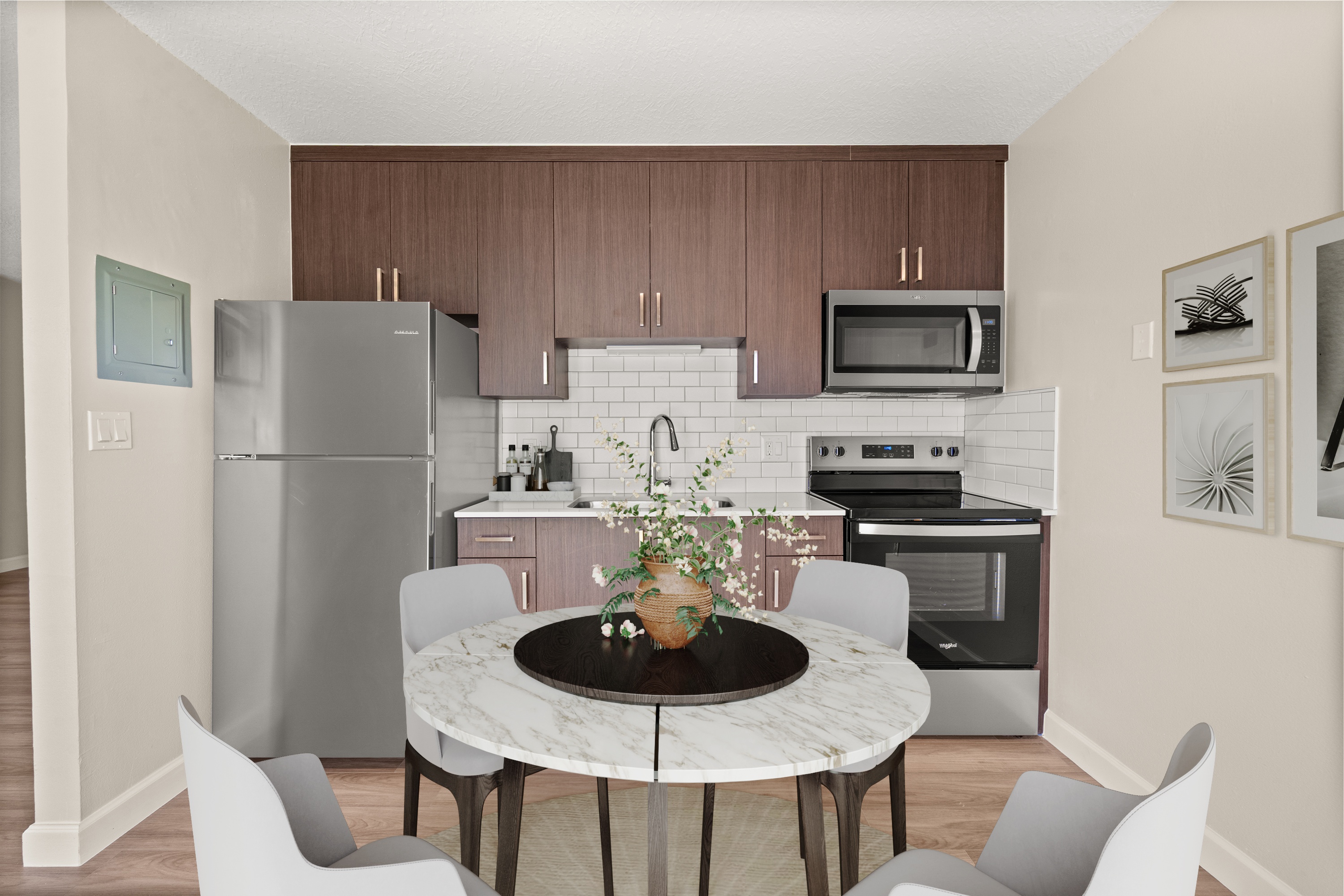 A kitchen with a refrigerator, microwave, oven, and a table with chairs.