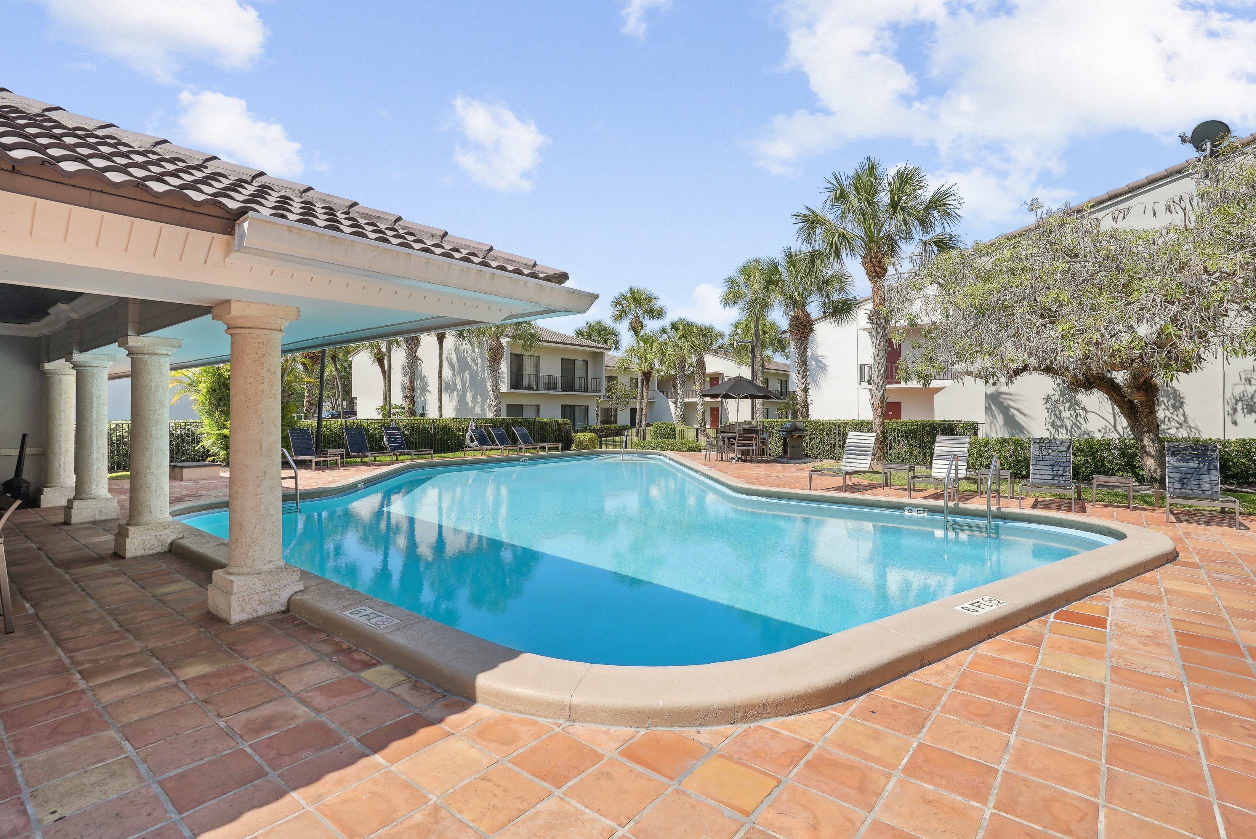 a large swimming pool in front of a house with palm trees