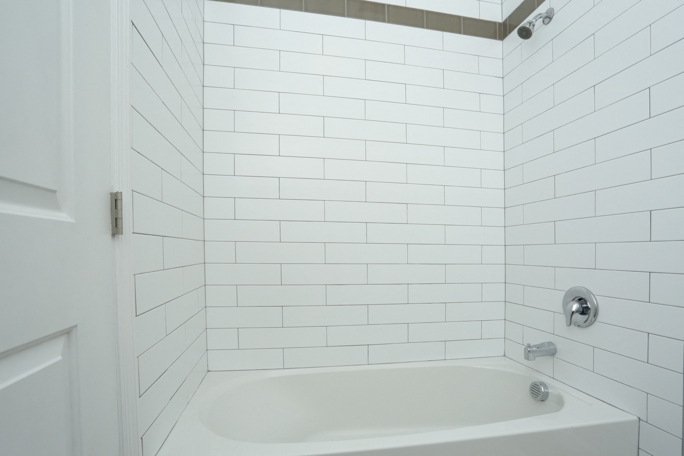 Bathtub in bathroom with white tile walls