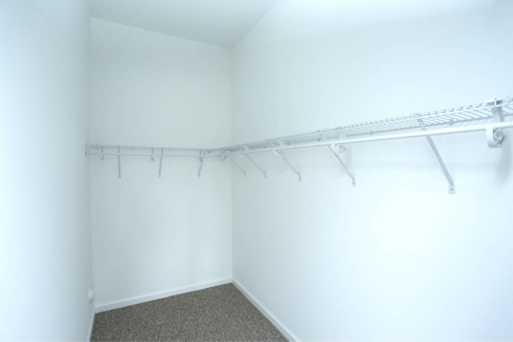 a white closet with a white wall and a white rack on the wall