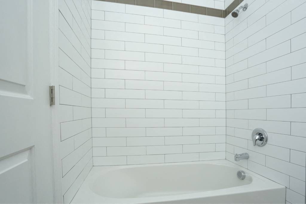 a white bathroom with a white tub and white tiles