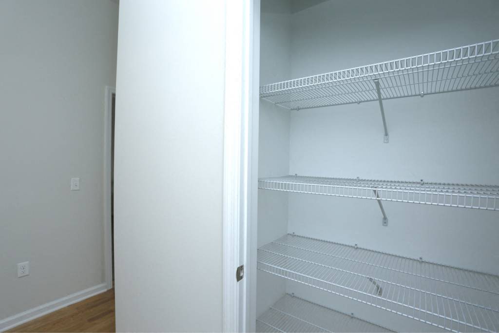 an empty closet with white shelves and a white door