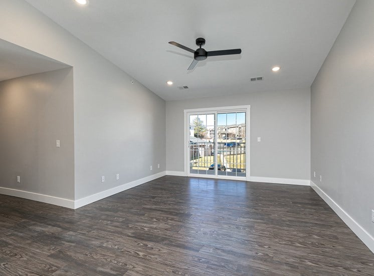 spacious living room with hardwood floors and sliding glass door at Quail Creek Apartments