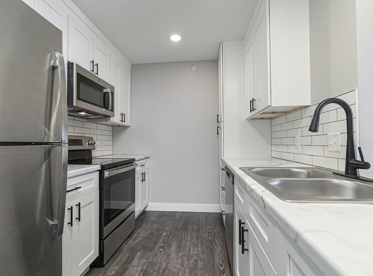 kitchen with stainless steel appliances and hardwood floors at Quail Creek Apartments