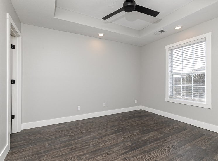 Apartment bedroom with hardwood floors and ceiling fan at Quail Creek Apartments