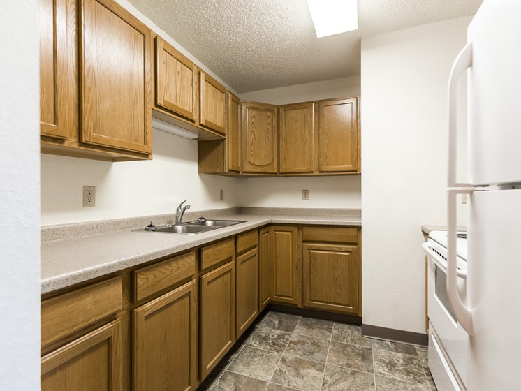 Bismarck, ND Arbor 400 Apartments. A kitchen with wooden cabinets and white appliances