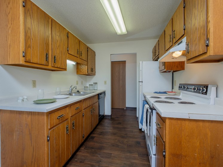 a kitchen with white appliances and wooden cabinets and a white stove. Fargo, ND Countryside Apartments