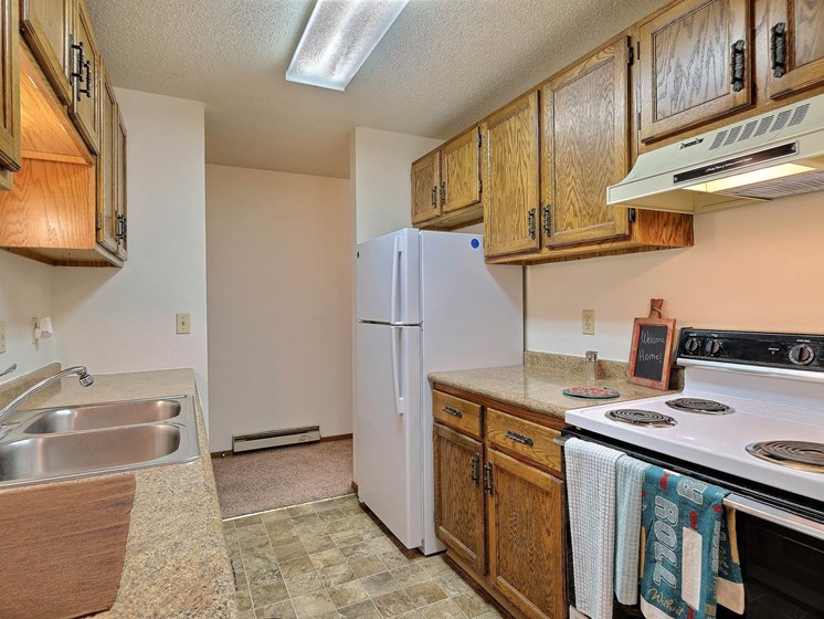 a kitchen with white appliances and wooden cabinets. Fargo, ND Pacific South Apartments.