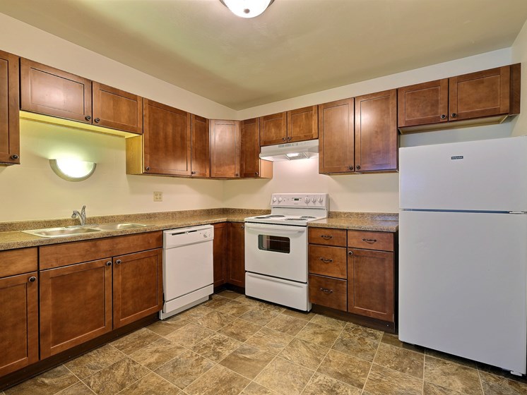 a kitchen with white appliances and wooden cabinets. Fargo, ND Spring Apartments
