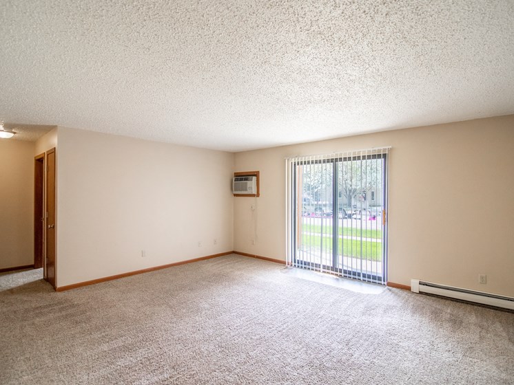 Bismarck, ND Eastbrook Apartments. A spacious living room with a sliding glass door leading to a yard