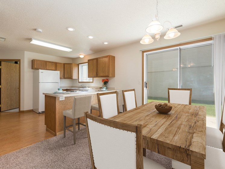 Bismarck Pebble Creek Apartments.with a glass sliding door that allows natural light to fill the space. The room showcases a well-appointed dining table, stylish seating, and a welcoming atmosphere for enjoyable meals and gatherings