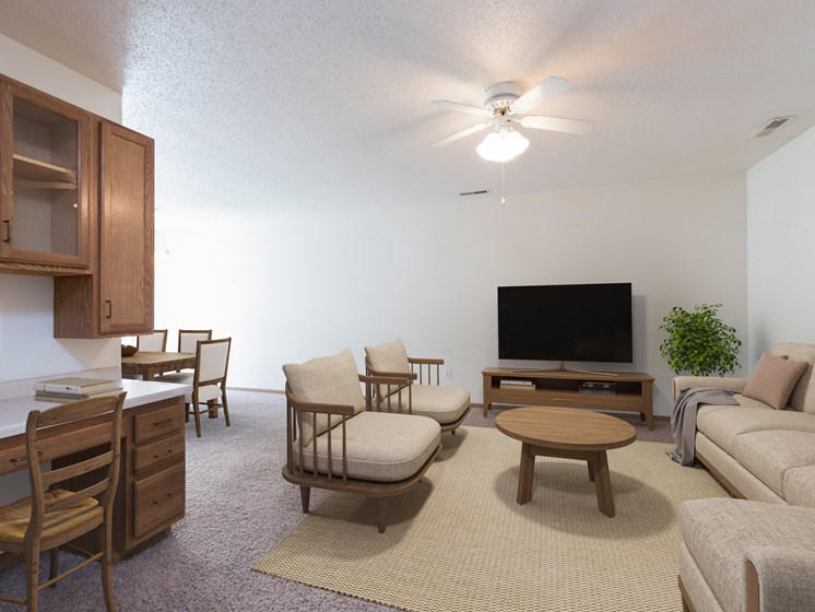 Bismarck Pebble Creek Apartments. The spacious living room is tastefully decorated with stylish furniture, ample natural light, and a cozy atmosphere. Theres overhead lighting with a touch of natural light from the dining room.