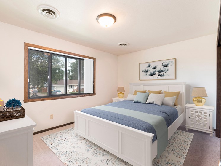 Bismarck, ND Riverpark Apartments  a bedroom with a large window and a large bed with blue bedding