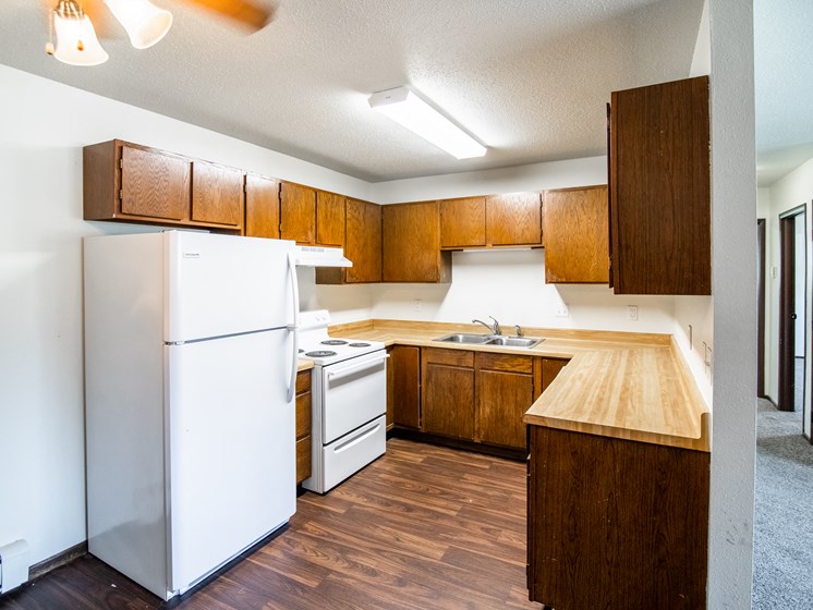 Bismarck, ND Rosser Apartments. a kitchen with a white refrigerator freezer next to a white stove top oven