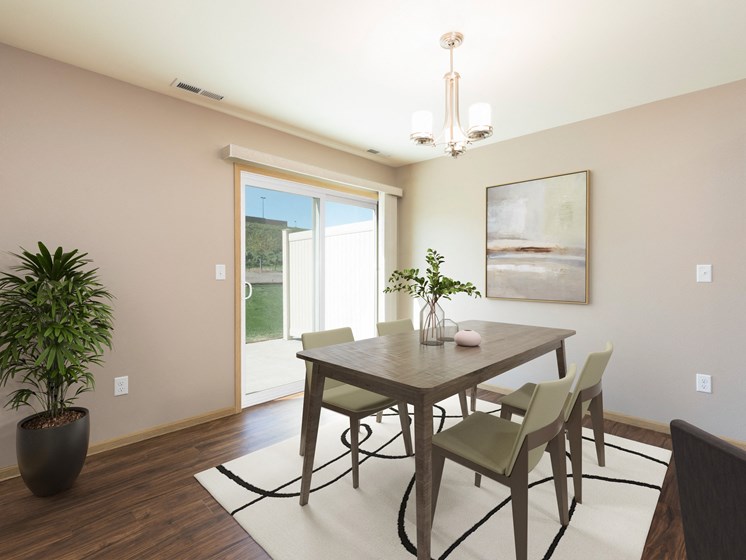 Bismarck, ND Stonefield Townhomes. The space features a well-appointed dining table with 4 chairs, modern kitchen appliances, and tasteful decor. Bright natural light fills the room from the glass sliding door.