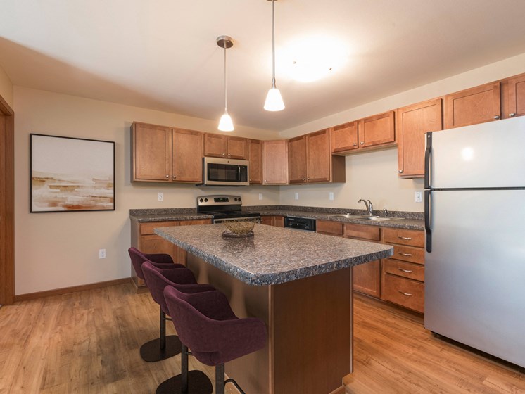 Bismarck, ND Stonefield Apartments. A kitchen with granite countertops and wooden cabinets