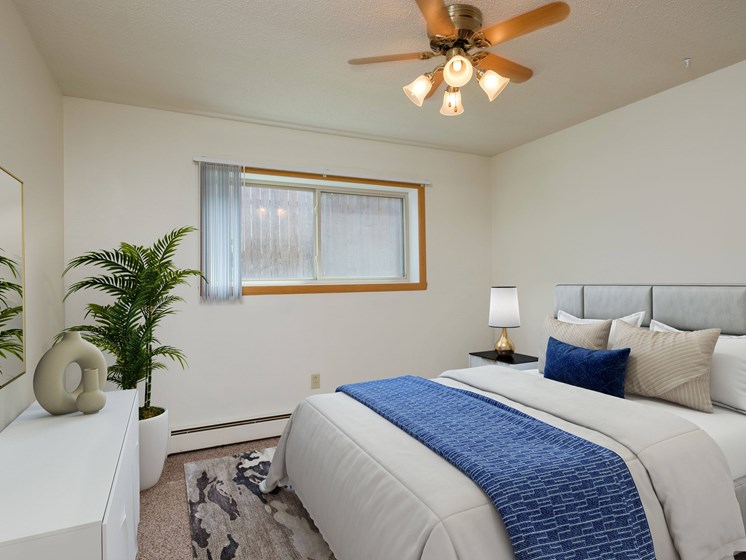 a bedroom with a large bed and a ceiling fan. Fargo, ND Country Club Apartments.