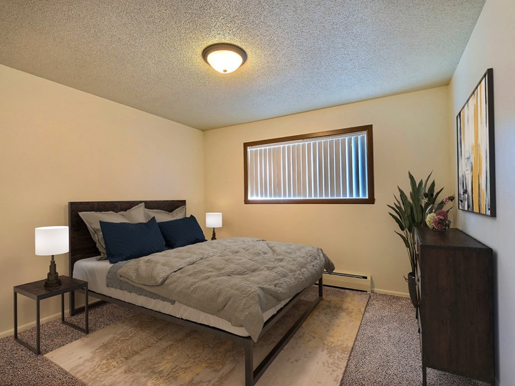 a bedroom with a bed and a window. Fargo, ND Emerald Apartments