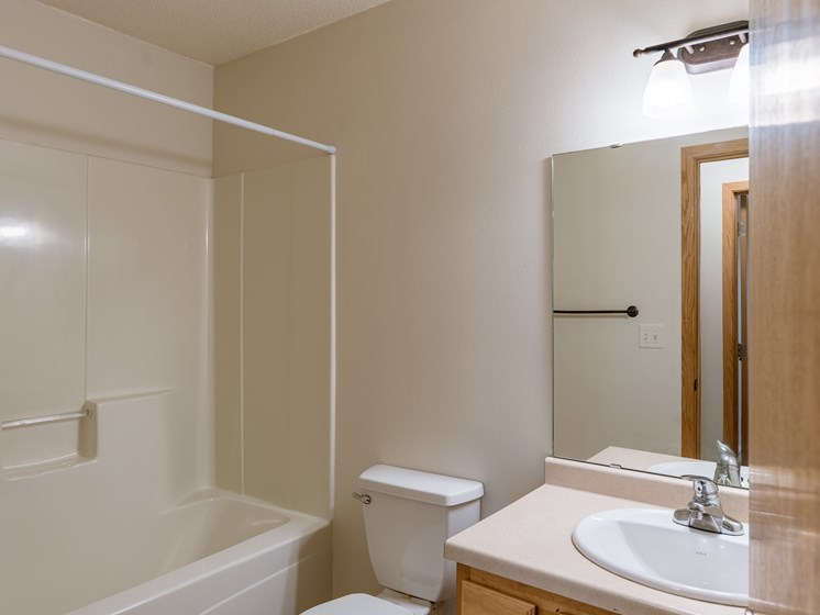 a bathroom with a sink and a toilet and a shower. Moorhead, MN Mallard Creek Apartments