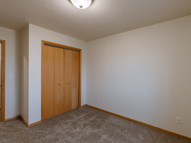 a bedroom with a closet and a door to a hallway. Moorhead, MN Mallard Creek Apartments