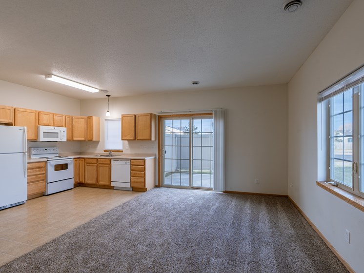 a kitchen and living room with a window and sliding glass door. Moorhead, MN Mallard Creek Apartments