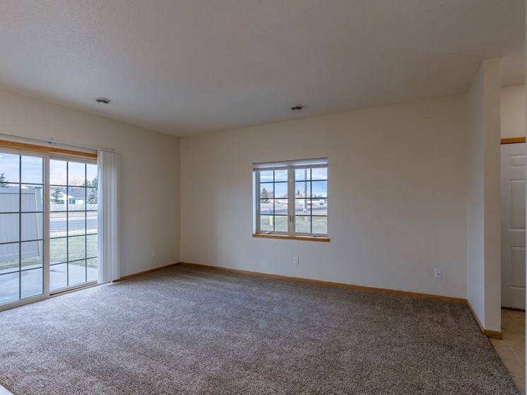a living room with a window and a glass sliding door. Moorhead, MN Mallard Creek Apartments