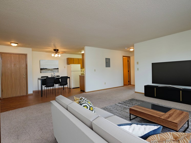 the living room of an apartment with a couch and a television. Fargo, ND Oak Court Apartments