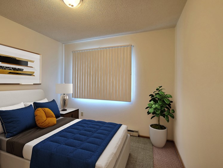a bedroom with a large bed and a potted plant. Fargo, ND Pacific South Apartments