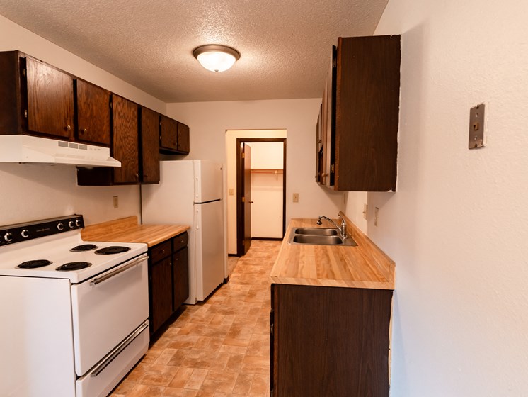 Fargo, ND Patricia Ann Apartments. A kitchen with white appliances and wooden cabinets