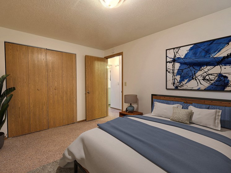 Fargo, ND Saddlebrook Apartments. a bedroom with a large bed and a potted plant
