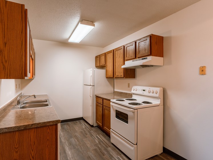 a kitchen with a stove refrigerator and sink. Fargo, ND Sargent Apartments