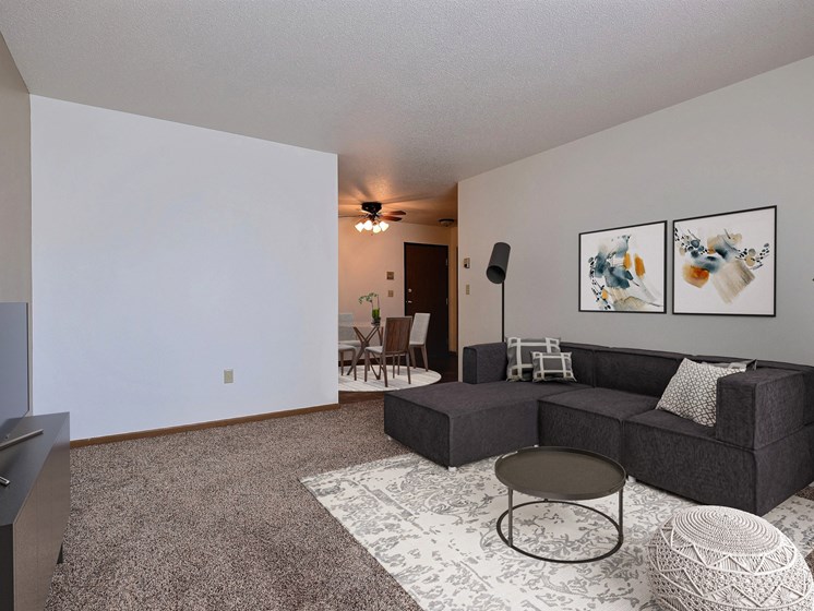 an empty living room with a couch and a tv. Fargo, ND Sterling Park Apartments