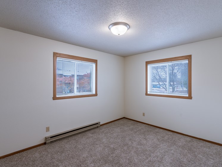 the living room of an empty house with two windows. Fargo, ND West Oak Apartments.