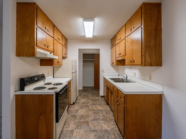 a kitchen with white appliances and wood cabinets. Fargo, ND Woodland Apartments