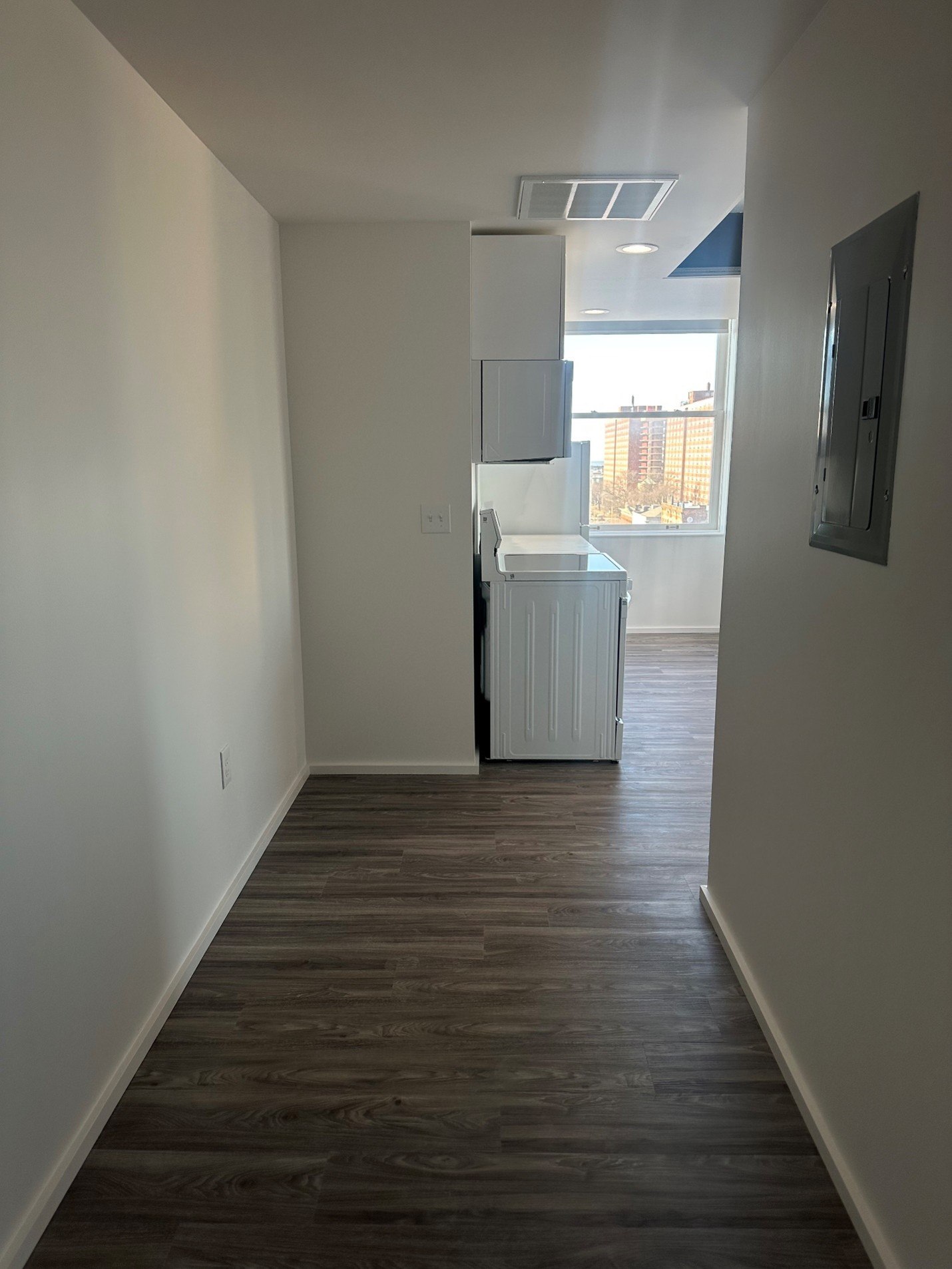 A long hallway with a white wall and a door on the right.