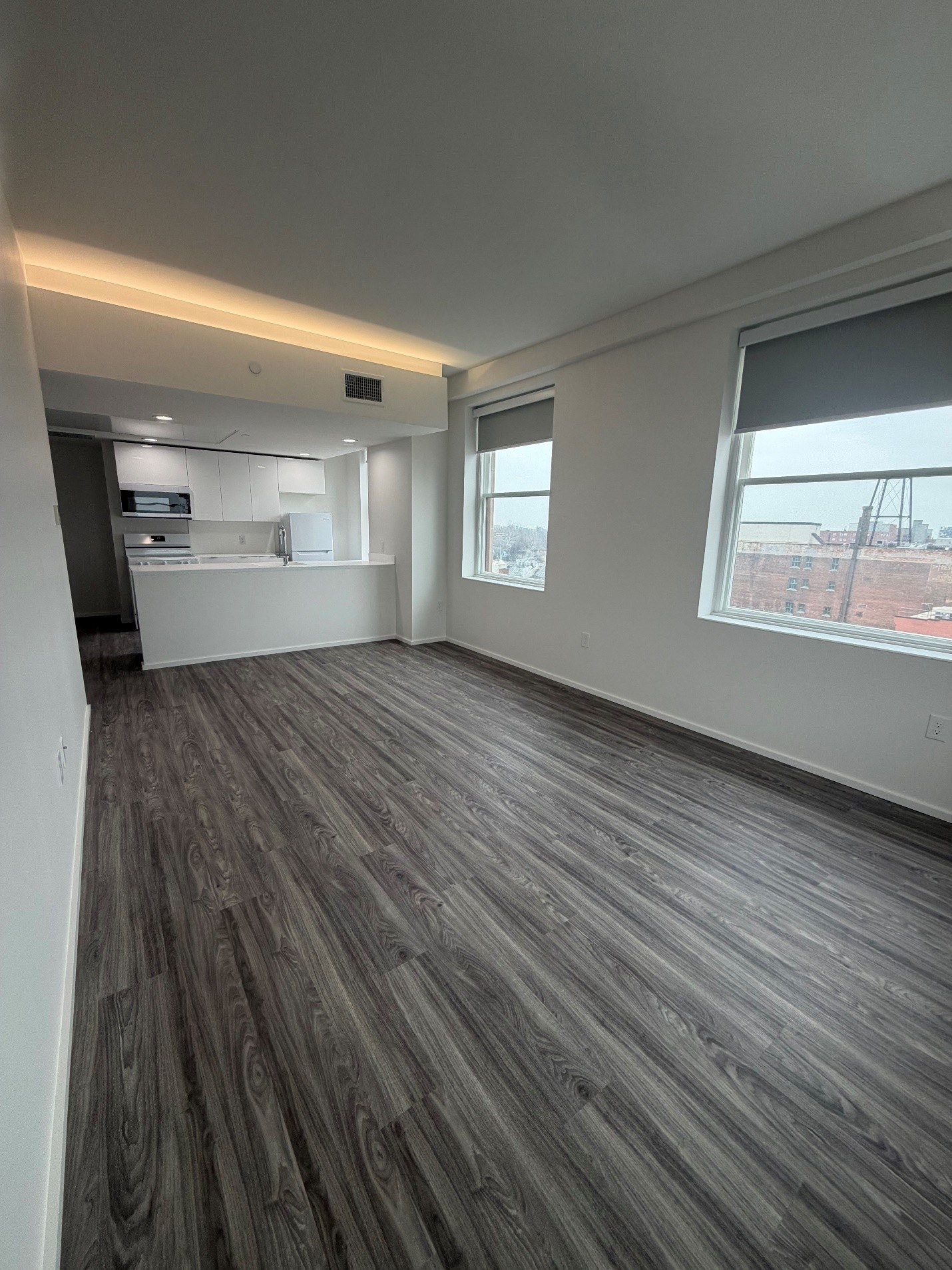 A room with a grey floor and a window overlooking a cityscape.