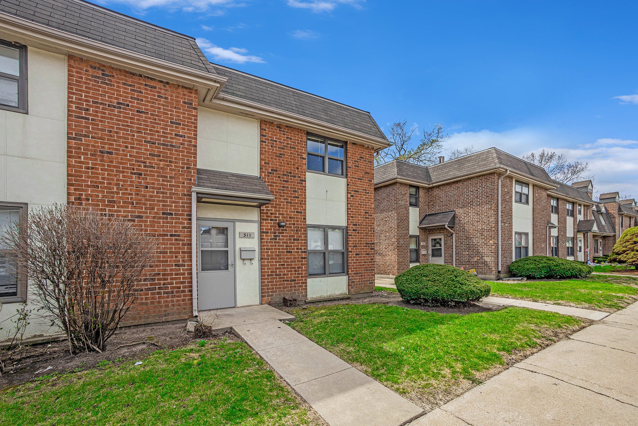A row of red brick houses with green lawns in front.