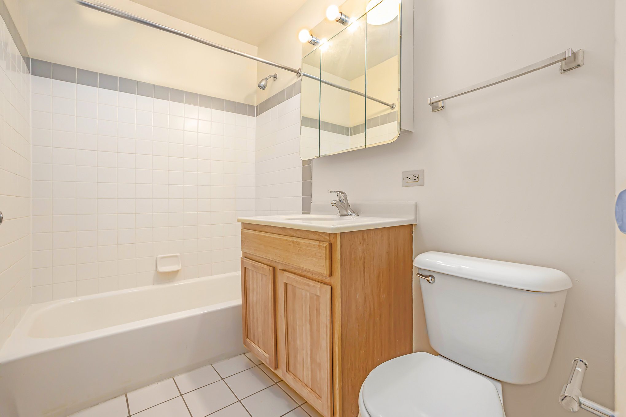 A white toilet sits next to a wooden cabinet in a bathroom.
