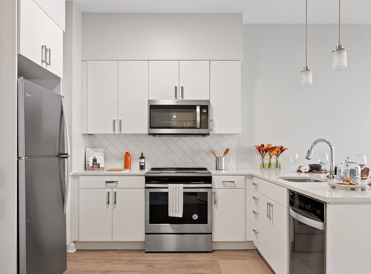 Kitchen with with white cabinets and stainless steel appliances at 23rd Place Apartments